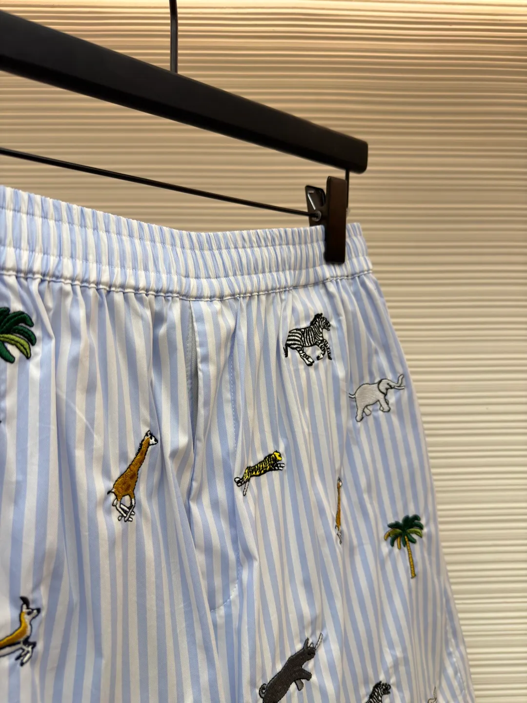 LOUIS VUITTON Animal and plant nostalgic style embroidered striped shorts ●Original version: purchased and developed by 14616 ●Item number: 1682542-A75 ●Fabric: cotton fabric ●Technology: embroidery production ●Color: blue ●Version: fitted version ●Weight: about 205 grams ●Size: S-M-L-XL ●Description: Made of high-count pure cotton poplin fabric. After pre-washing process, it feels smooth and breathable. It has both drape and stiffness, and is not easy to wrinkle and deform. The blue and white vertical stripes on the body are woven with yarn-dyed technology, and the texture is clear and does not fade. The animal and coconut tree patterns are presented with sophisticated embroidery technology. The embroidery threads are full of color and the stitches are dense. The patterns are three-dimensional and vivid, forming a rich visual hierarchy with the stripe base. The shirt has a Cuban collar style, with smooth necklines, custom mother-of-pearl buttons at the placket, and a warm texture. The overall shape is loose, the shoulder joints are straight and fine, the cuffs are cuffed with exquisite craftsmanship, custom accessories and three logos are complete, and the details are full of luxury craftsmanship. It is suitable for casual vacations and daily outings, etc. The overall wiring is straight and delicate, the fabric is comfortable and soft, and the color is consistent without color difference. It can be matched with the same style to create a fashionable look and control various occasions. Customized accessories, complete with three standards, same style for men and women!